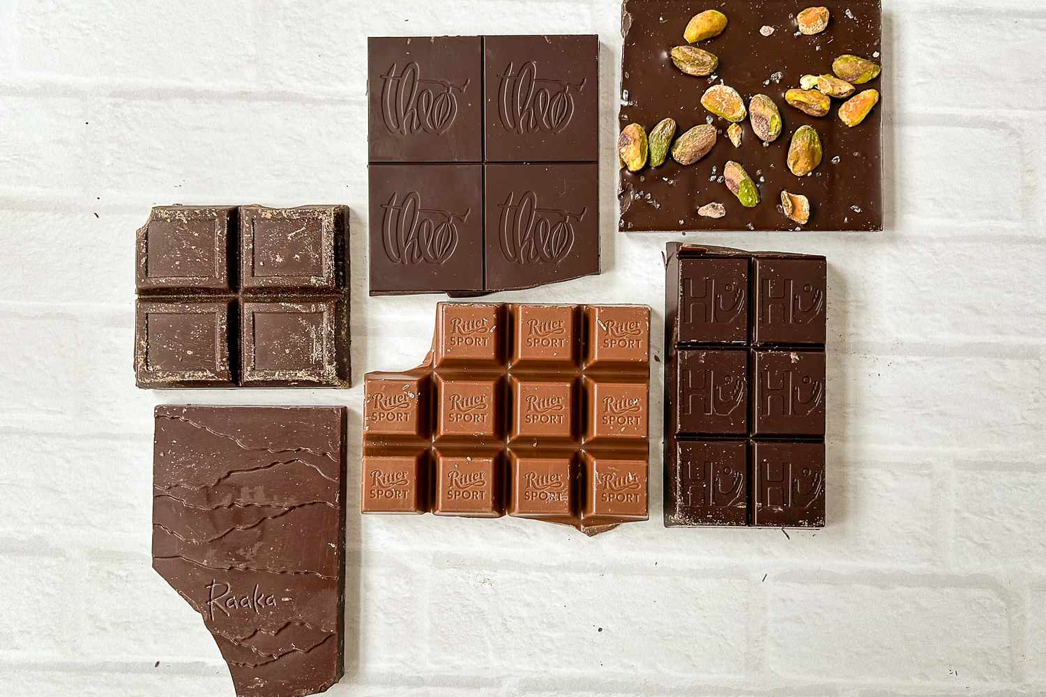 Diversas barras de chocolate de origem dispostas sobre tijolos brancos